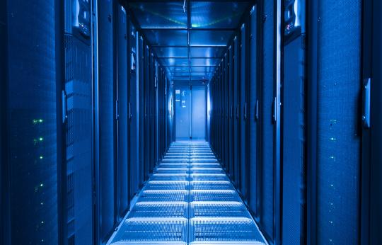 Image of the JASMIN hardware located at the Harwell Campus in Oxfordshire. It shows a corridor of servers which are emitting a blue light.
