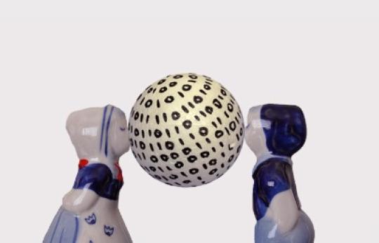 Dutch ceramic figures kissing a globe decorated with 0s and 1s