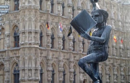 Photo of statue of reading boy pouring water over his head from a cup.
