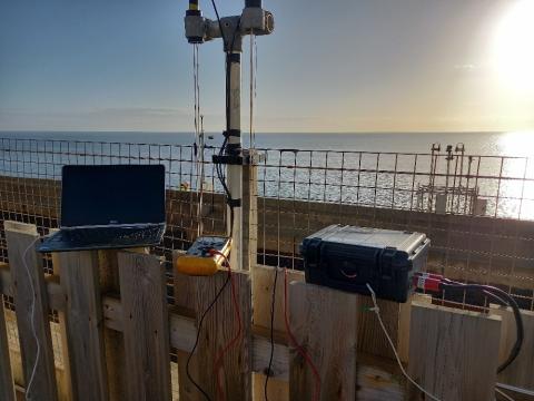 A photo of a laptop and other scientific equipment by the sea